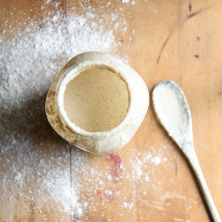 a jar of sourdough starter with a spoon next to it