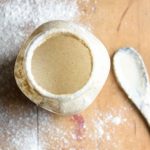 a jar of starter with flour and a spoon next to it