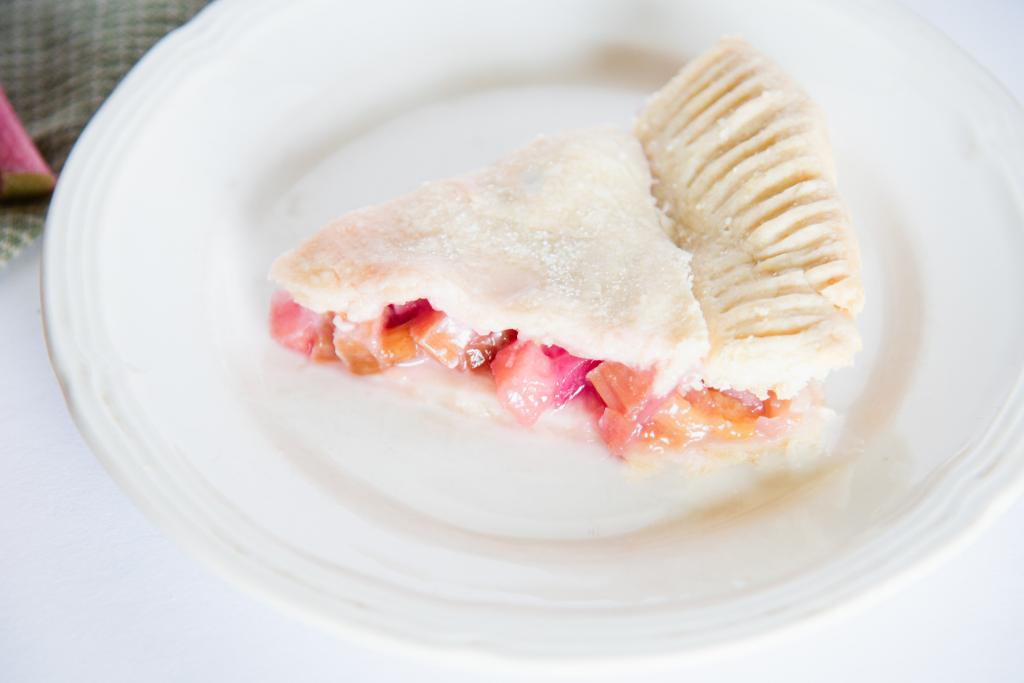 a piece of rhubarb pie sitting on a plate with a fork next to it