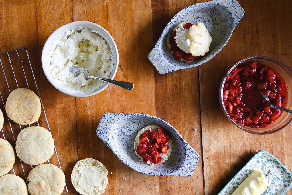 a finished strawberry shortcake with the ingredients around it and a second shortcake with just strawberries on it 