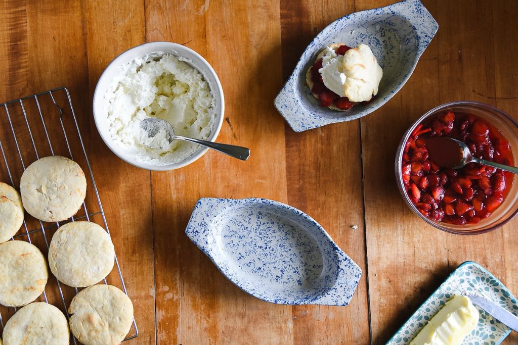 a finished strawberry shortcake with the ingredients around it and an empty dish