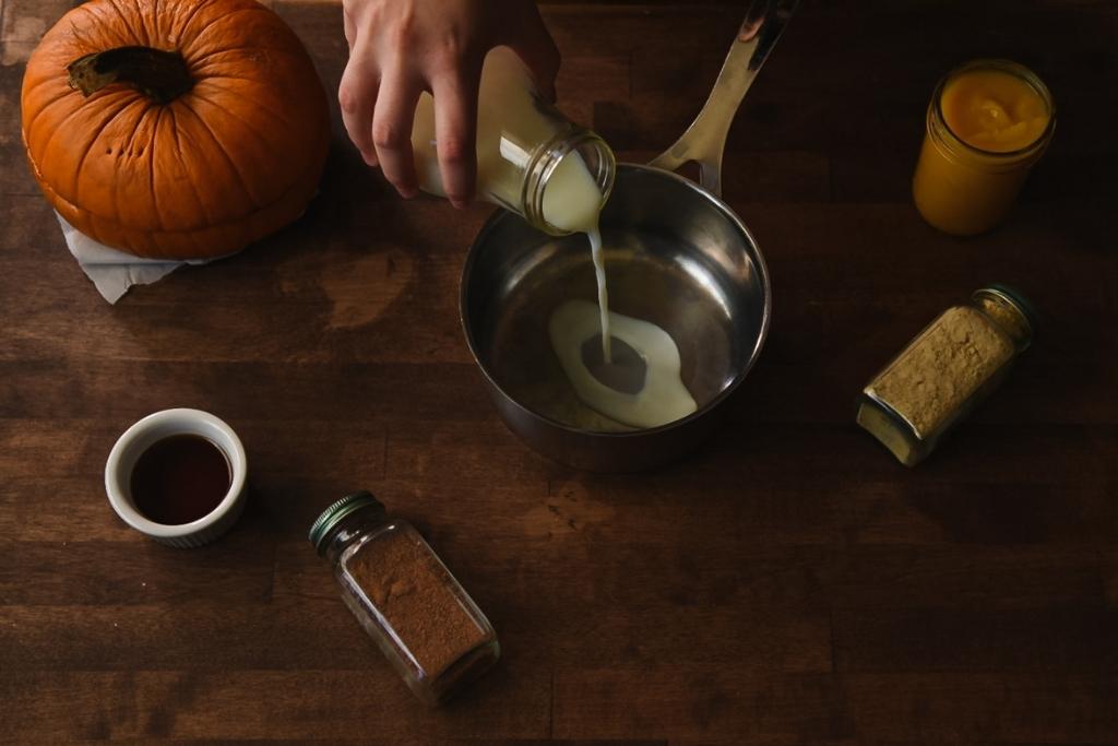 someone pouring milk from a glass jar into a pan