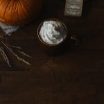 finished pumpkin spice latte with a pumpkin some wheat and a little sign next to it