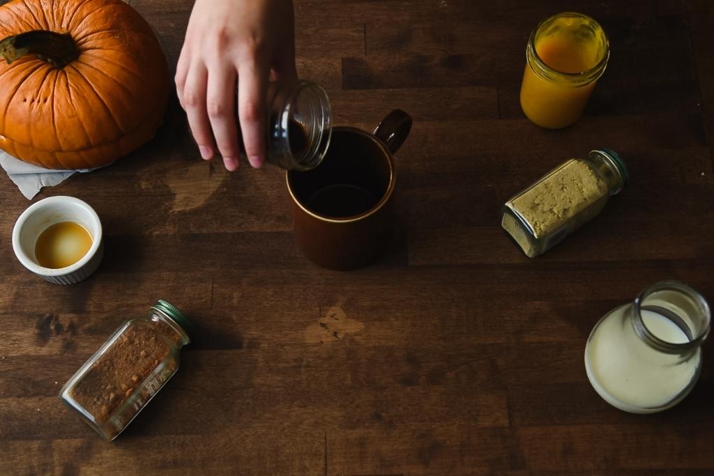 someone pouring coffee from a jar into a coffee mug