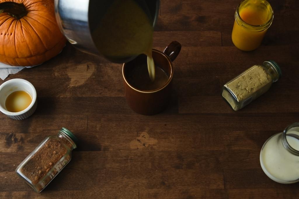 spiced milk into a coffee mug that has coffee in it 