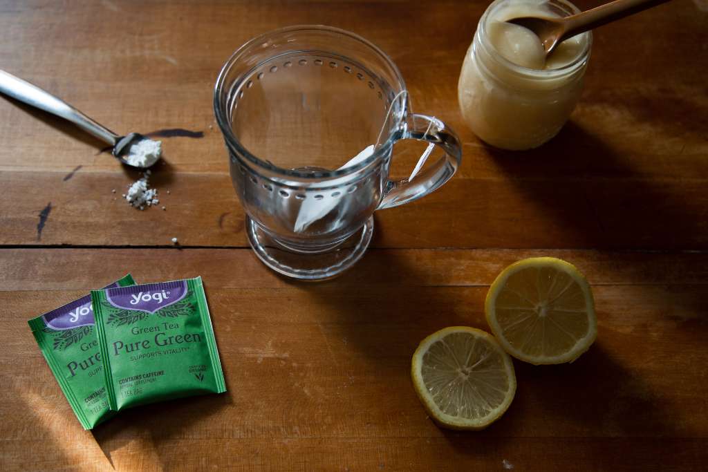 a glass cup with a tea bag in it. And cold-fighting tea ingredients around it