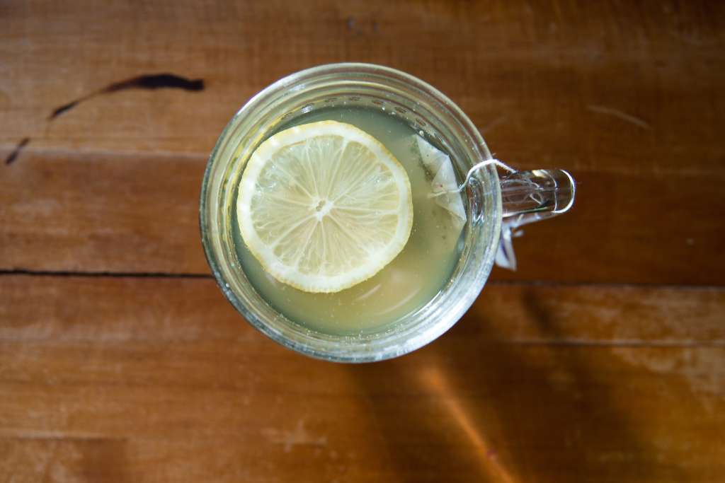 a cup of green tea with a lemon slice floating on it