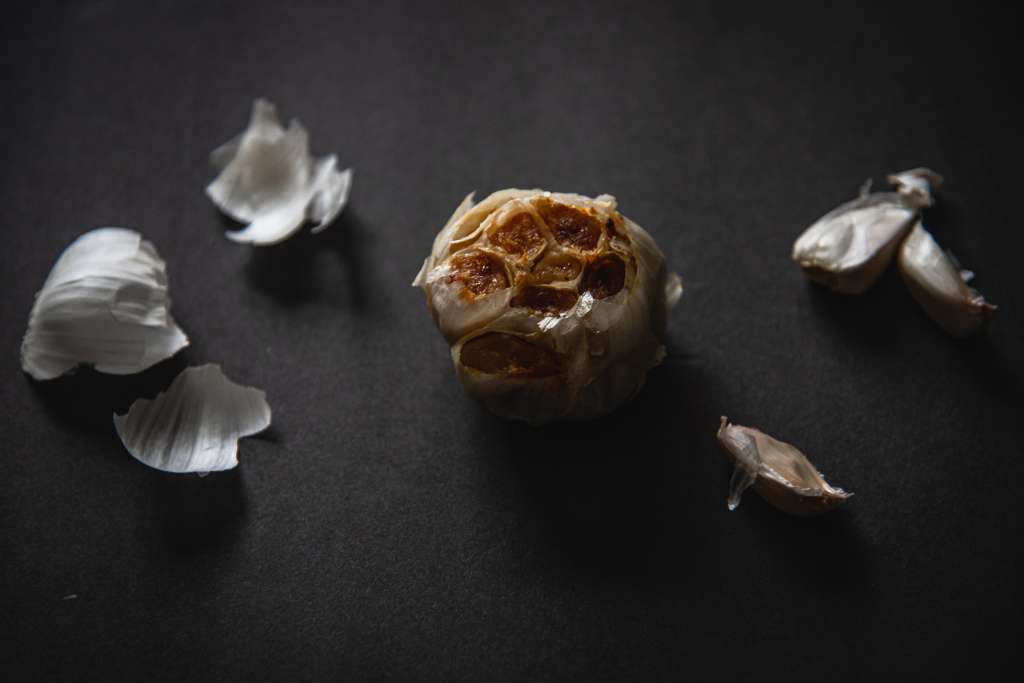 a roast bulb of garlic, with some clove on one side of it and some peels on the other.