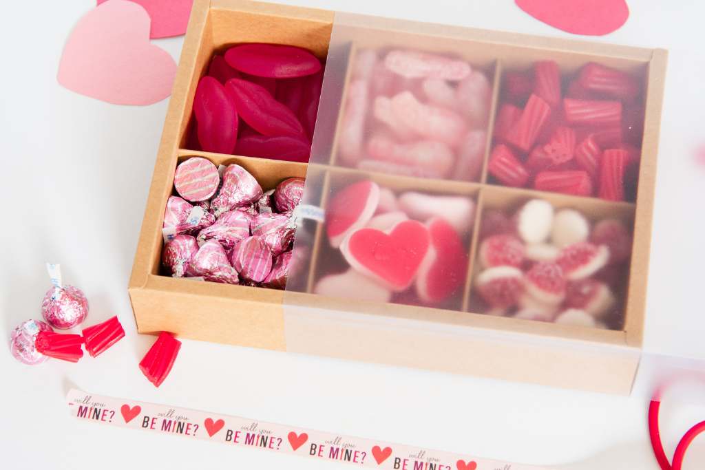 a valentine's day candy box with the cover part way on it, there are some candies and  valentine's decortations