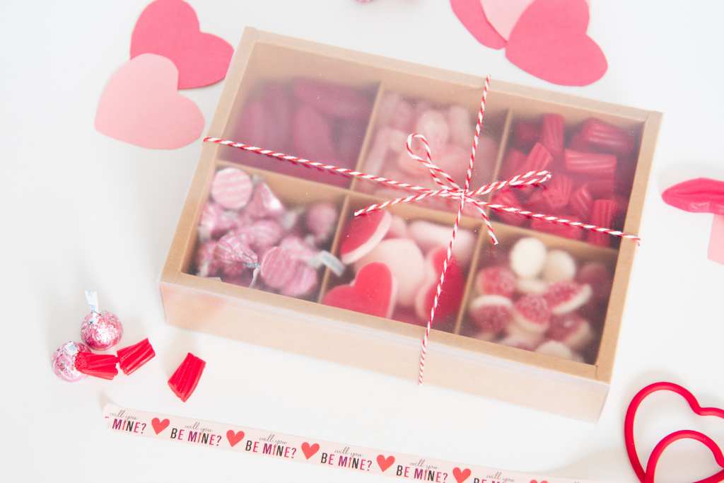 a finished valentine's candy box with it's cover on and a red and white string tied around it