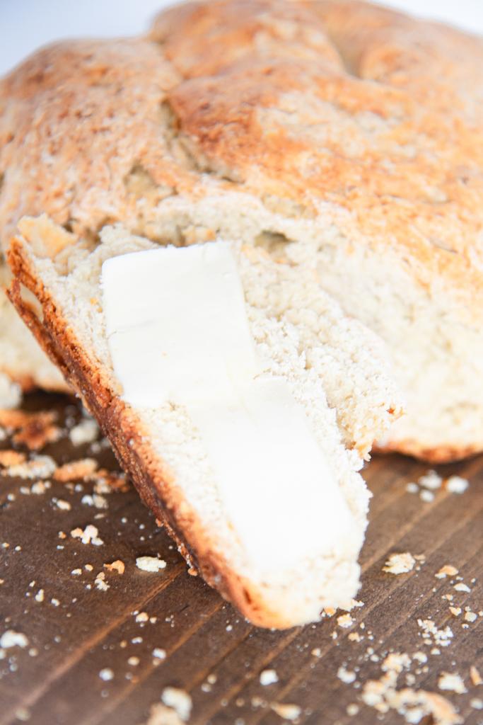 a slice of soda bread with butter, propped up against the loaf of bread