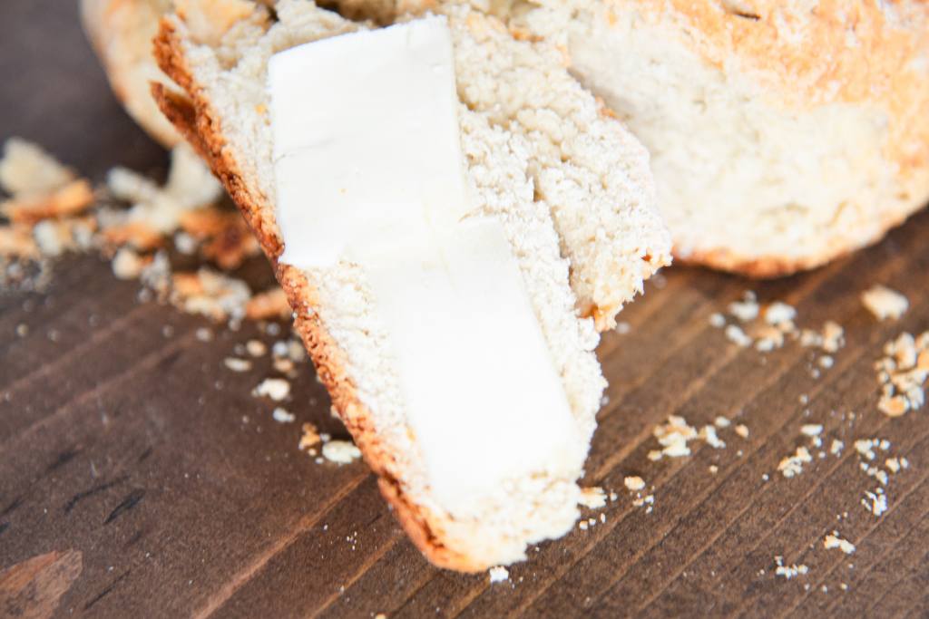 a slice of soda bread with butter leaned against the loaf of bread