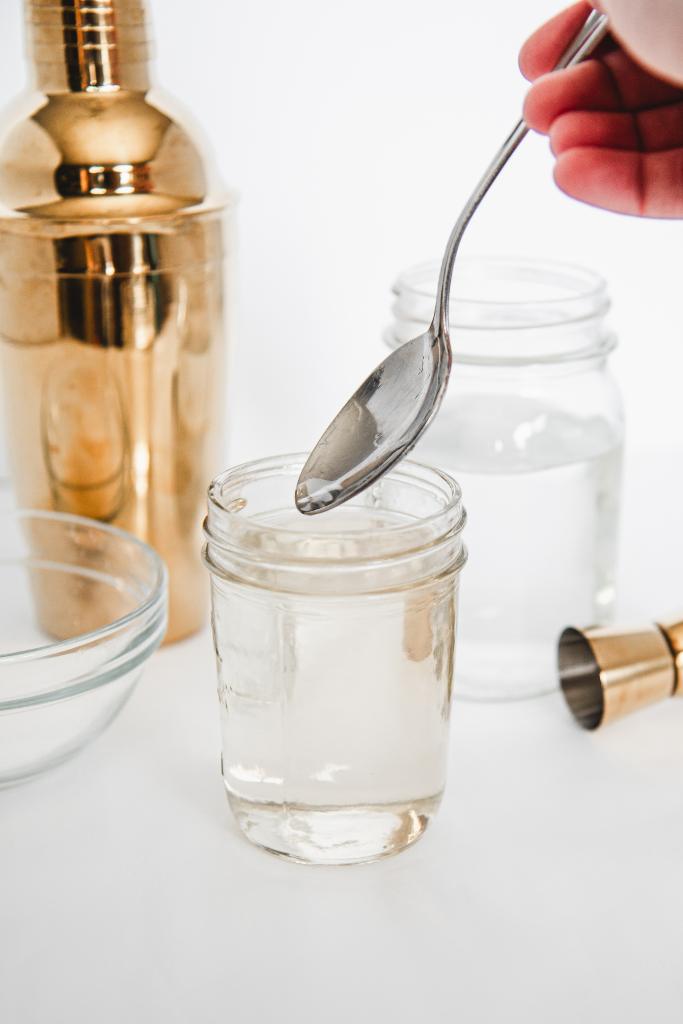 someone lifting a spoon out of a jar of simple syrup