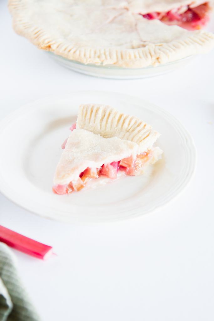 a slice of pie on a plate, you can see the rest of the pie behind it